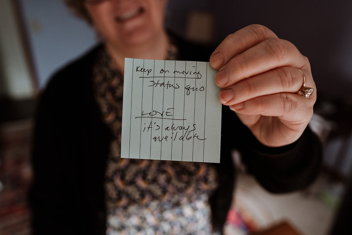 A closeup of a hand holding a piece of paper with something writen on it