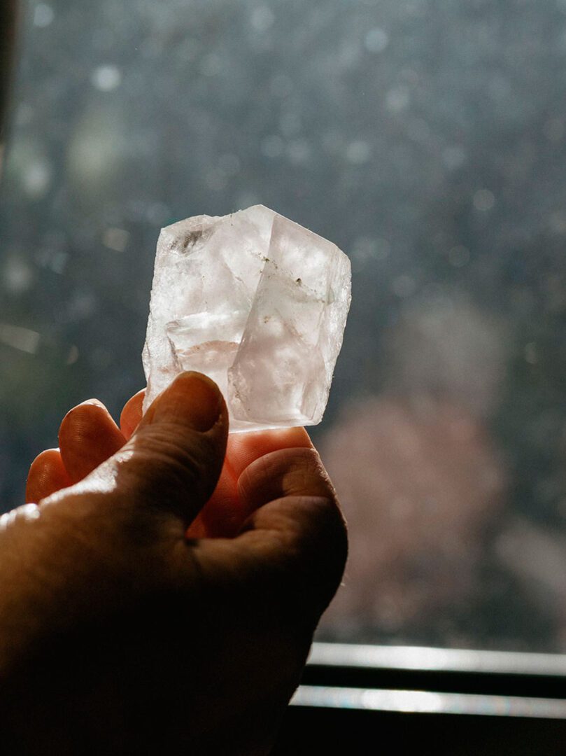 A closeup of a hand holding a piece of white crystal